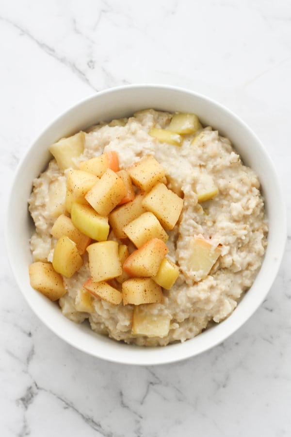 apple cinnamon oatmeal in a white bowl topped with stewed apples.