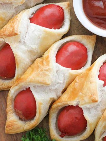 pigs in a blanket on a wooden serving board with text overlay "air fryer pigs in a blanket".