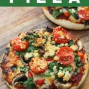 pizzas on a wooden serving board with text overlay "spinach & feta pizzas".