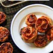 pizza scrolls piled up on a white plate with text overlay "air fryer pizza pinwheels".