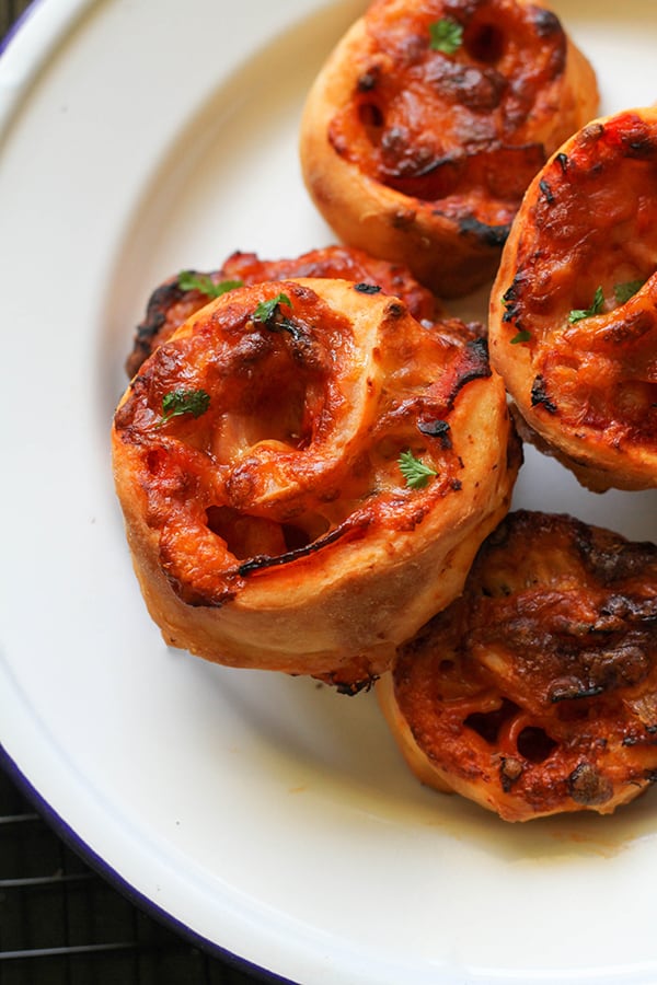 pizza pinwheels piled up on a white plate.