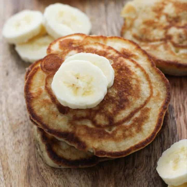 banana pikelets stacked on top of each other on a wooden board.