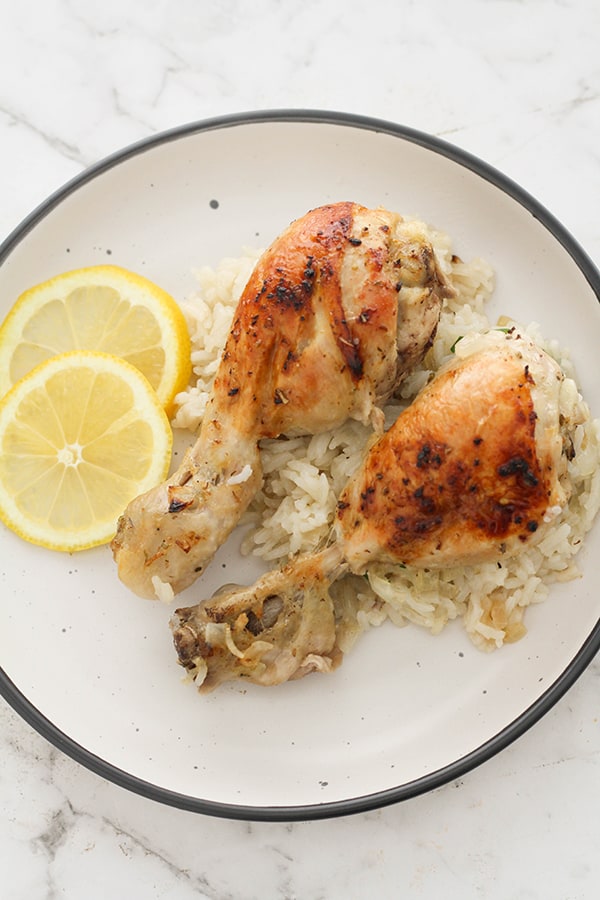 chicken drumsticks and rice on a white plate.