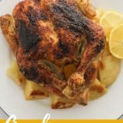 roast chicken and potatoes on a white plate with text overlay "Greek roast chicken and potatoes".