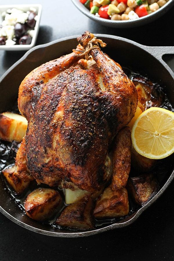 greek roast chicken and potatoes in a cast iron pan.