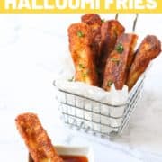 halloumi fries in a wire basket with text overlay "must try halloumi fries".
