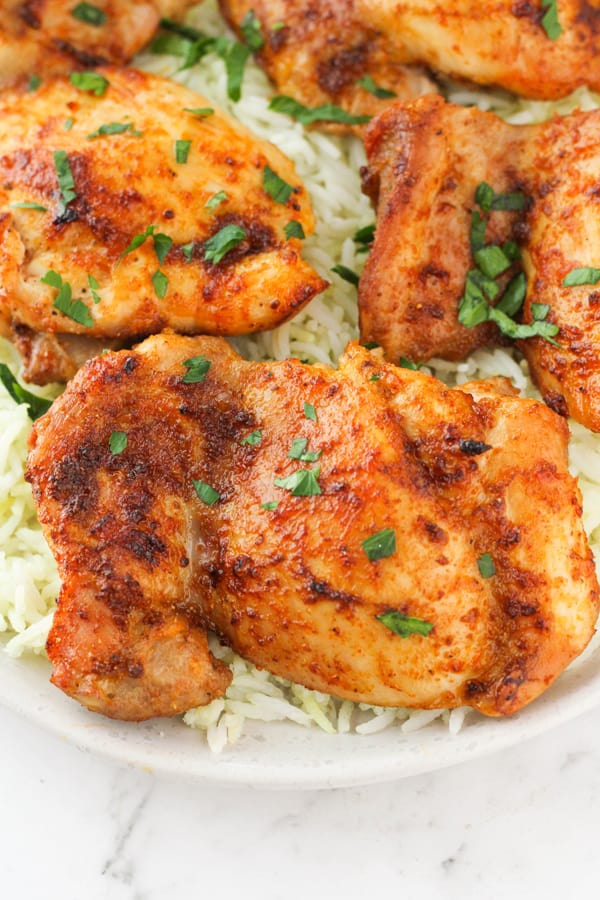chicken thighs on top of a bed of rice with parsley.