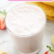strawberry smoothie in a glass surrounded by strawberries and banana slices with text overlay "strawberry yogurt smoothie".