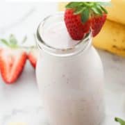 smoothie in a small bottle topped with a strawberry and text overlay "strawberry banana smoothie".