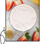 strawberry smoothie in a glass surrounded by strawberries and banana slices with text overlay "strawberry yogurt smoothie".