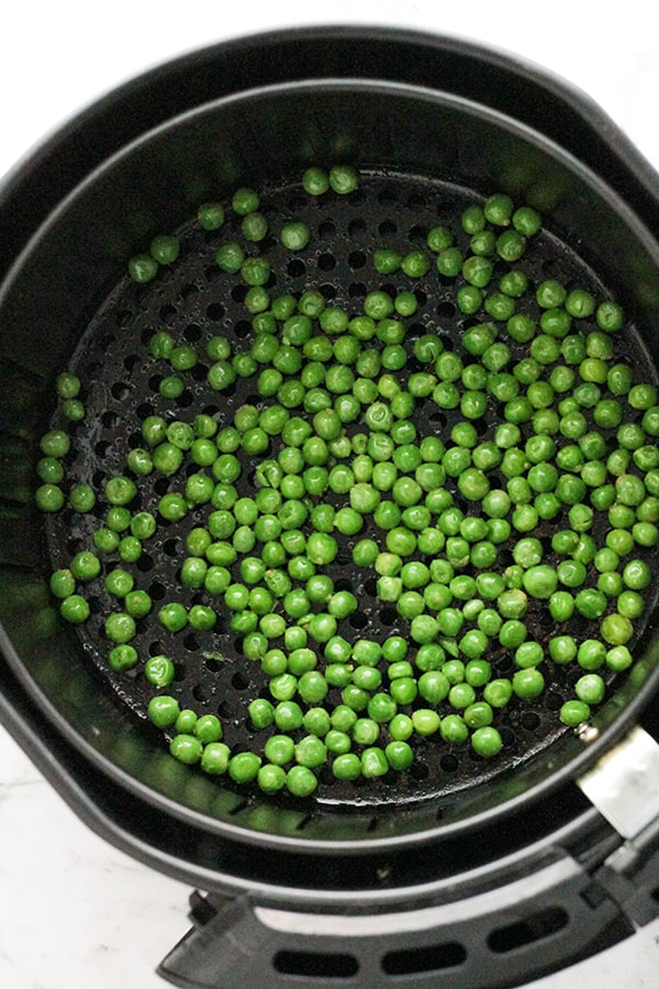 green peas in an air fryer basket.