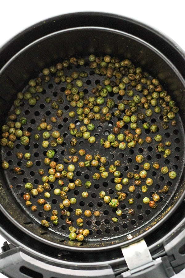 roasted peas in an air fryer basket.