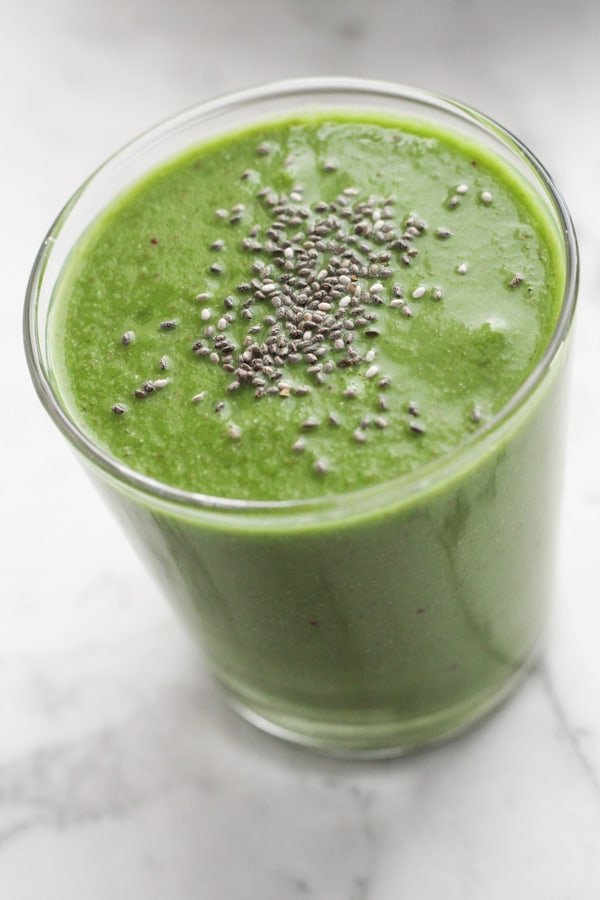 green smoothie in a glass topped with chia seeds.