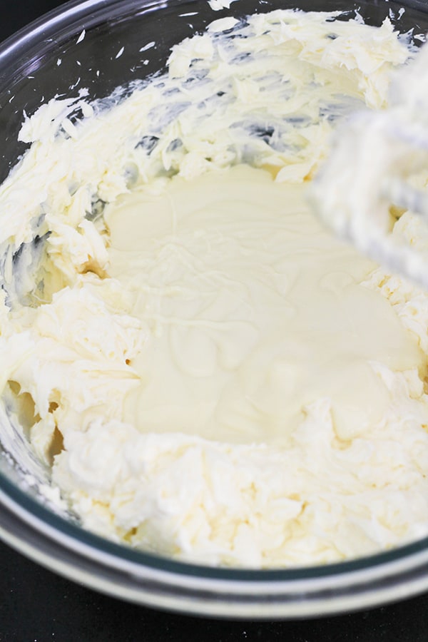 white chocolate mixed with cream cheese and sugar in a mixing bowl.