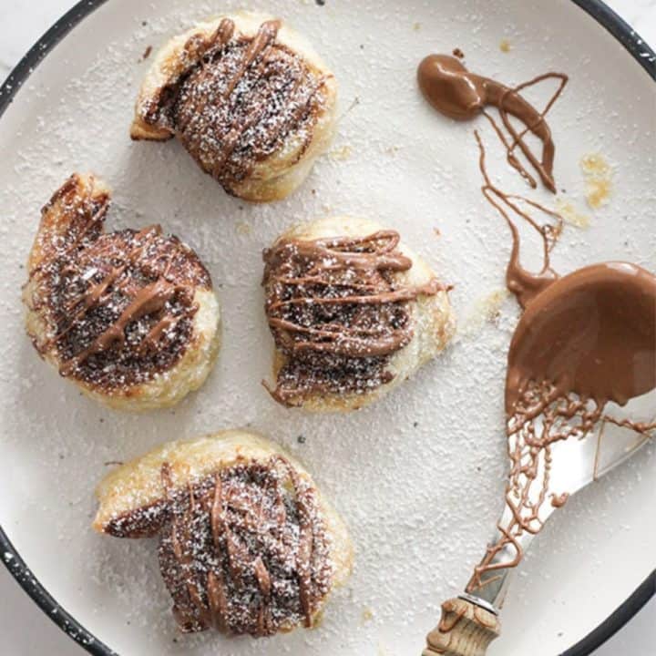 pinwheels on a white plate drizzled with chocolate.