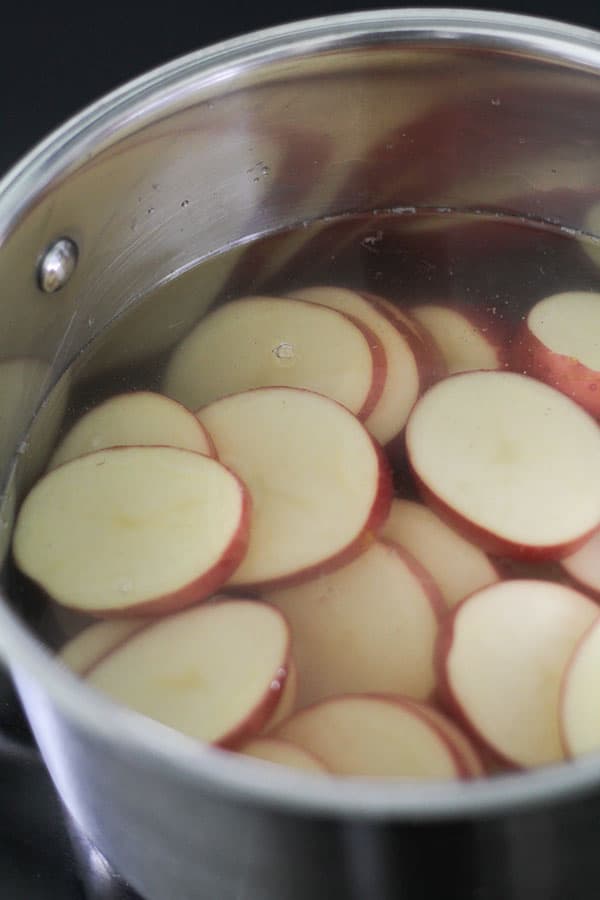 potato rounds in a saucepan covered in water.