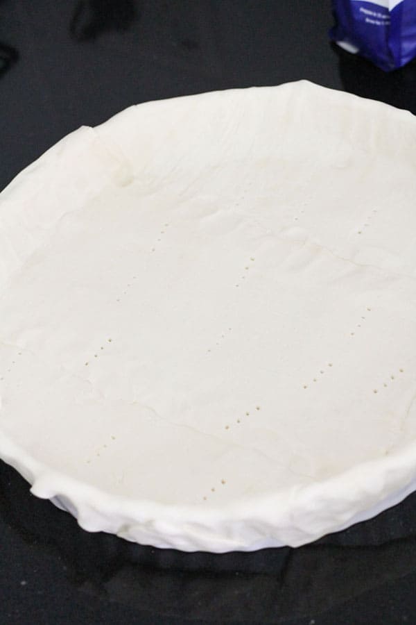 puff pastry lining a quiche dish.
