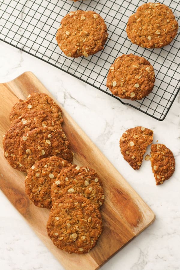 anzac biscuits on a serving board and a wire rack.
