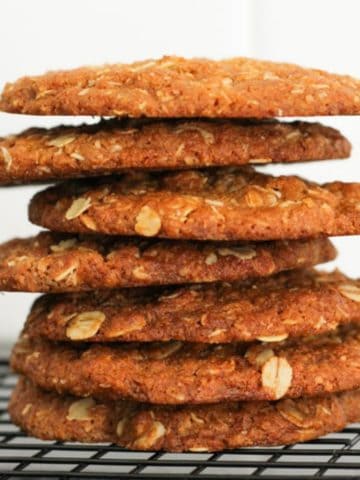 anzac biscuits stacked together on a wire rack.