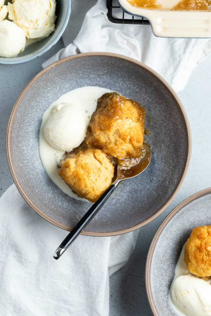 golden syrup dumplings in a bowl with ice cream.