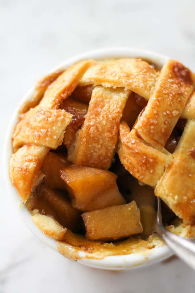 a fork scooping apple pieces from a mini apple pie.