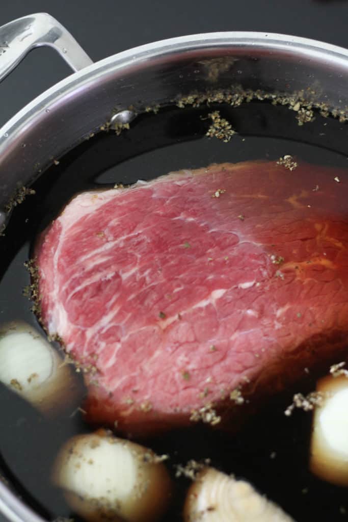 corned beef in a saucepan filled with water