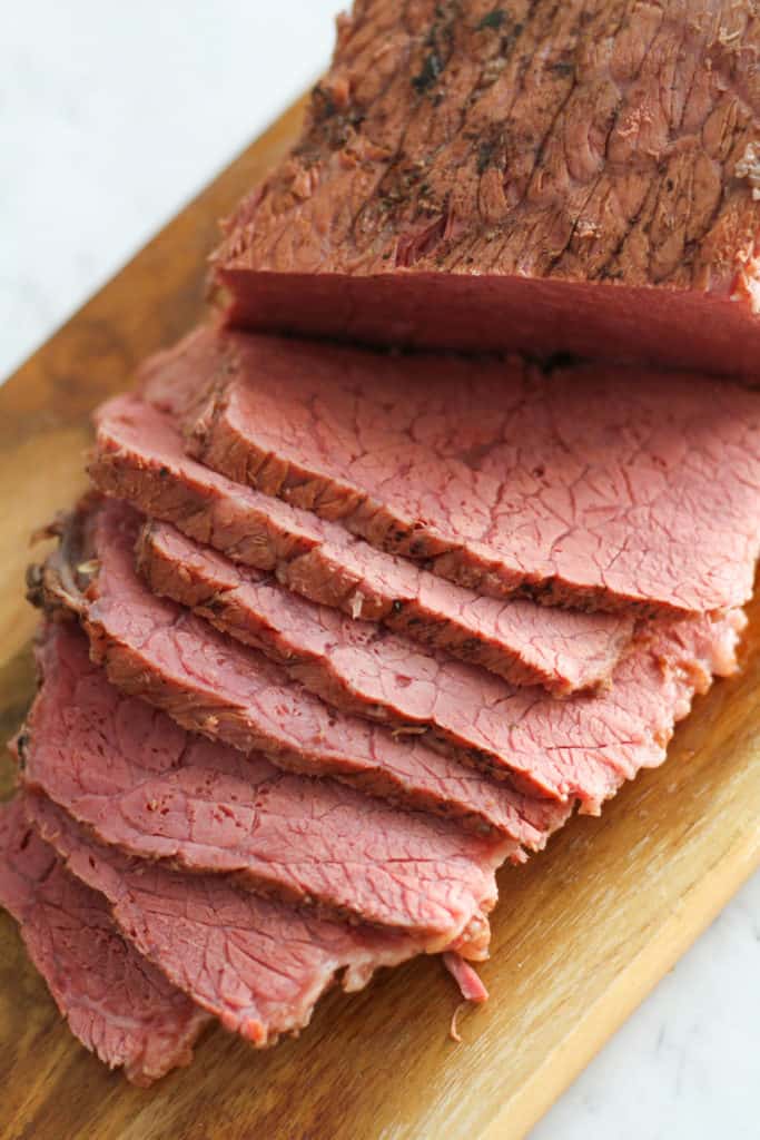 slices of corned beef on a wooden serving tray.