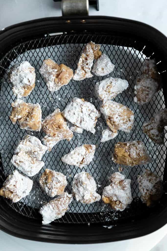 raw chicken pieces in an air fryer basket ready to be cooked.