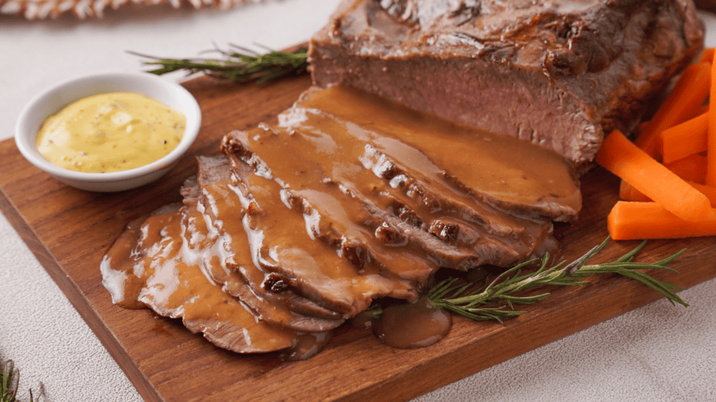 Roast Beef with veggies, gravy and mustard on a wooden coaster